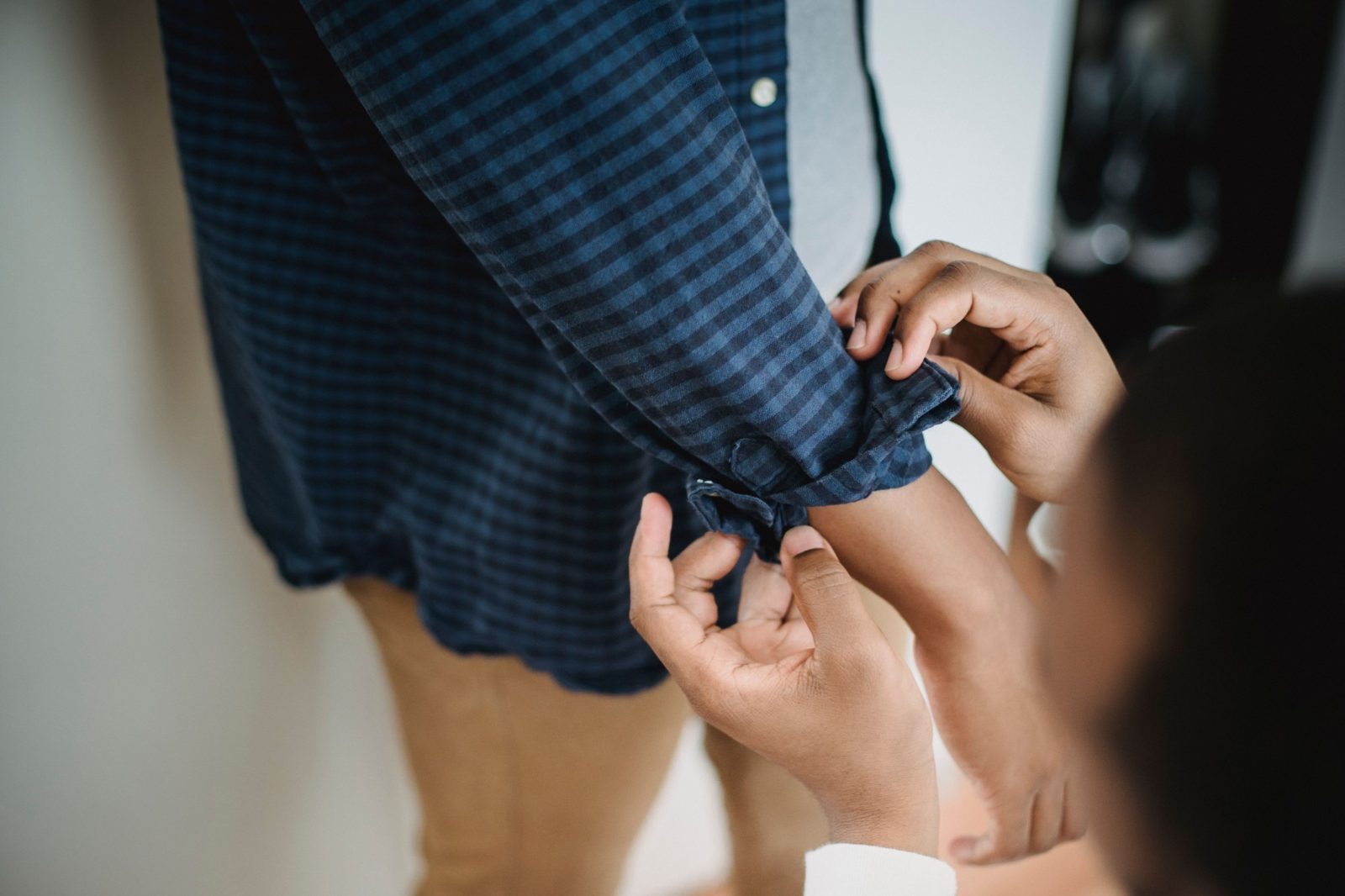 A support worker fastens the cuff of someone's shirt as they get dressed.